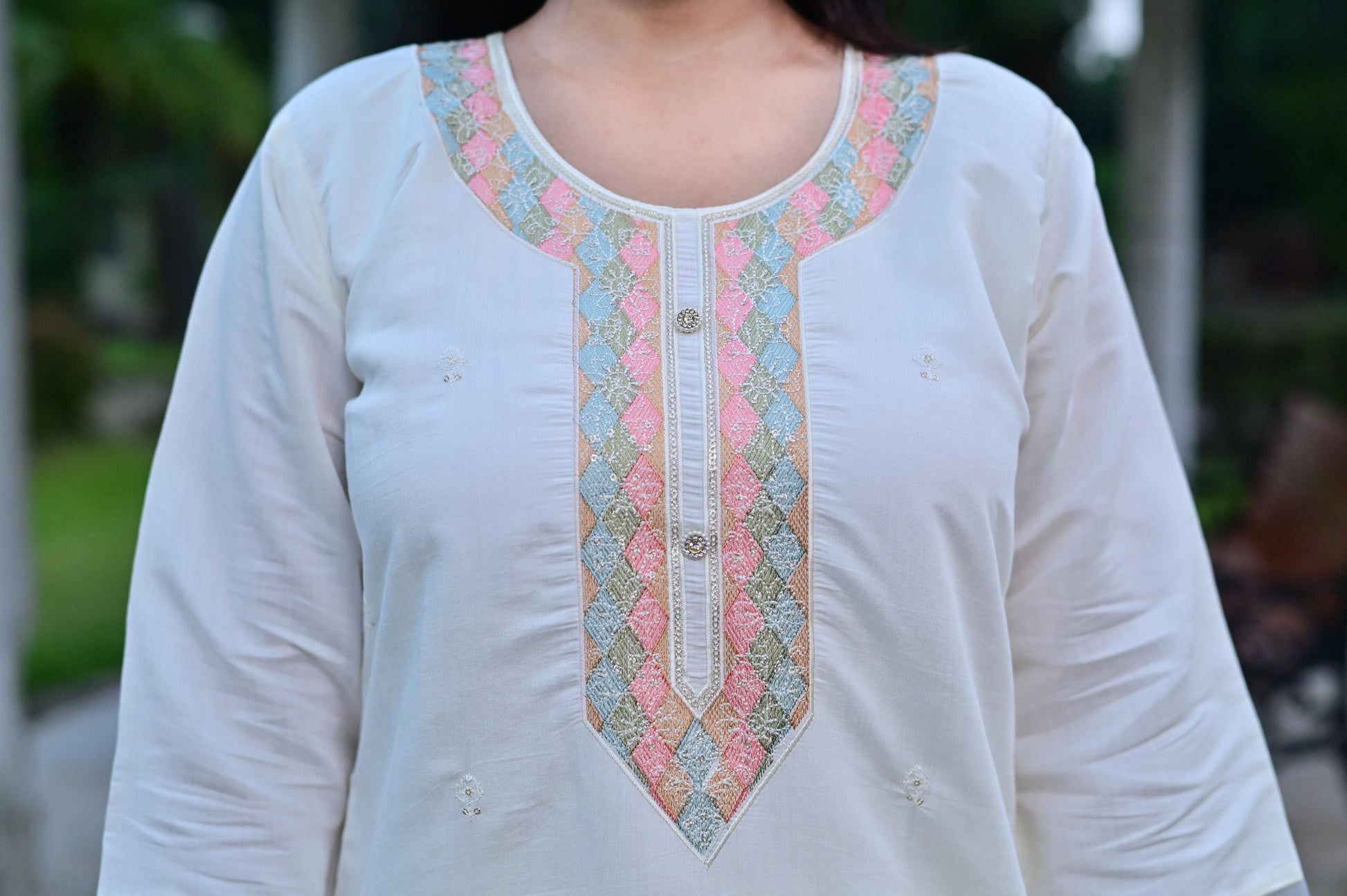 Close-up of off white kurta with pastel accents on neckline and sleeves